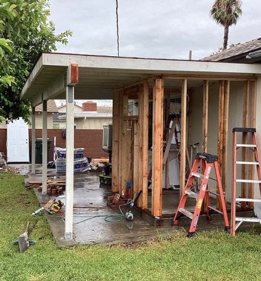 A house under renovation, featuring a ladder and various tools scattered around the work area.