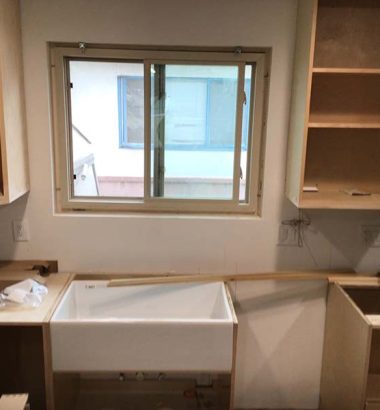 A kitchen under construction featuring cabinets and a sink, with tools and materials visible around the area.