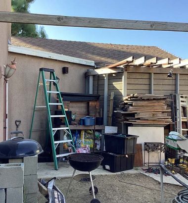 A backyard scene featuring a grill and two ladders positioned on the grass.