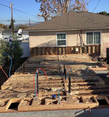 A house under construction with a wooden deck being built in the foreground.