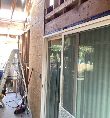 A man is using a ladder to work on the exterior of a house.