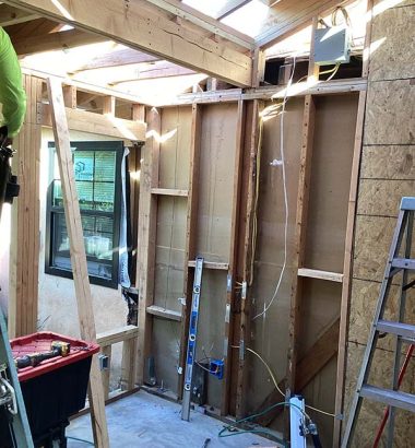 A man is using a ladder to work on the exterior of a house.