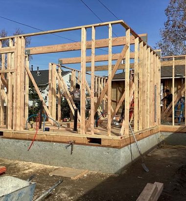 A house under construction, showcasing wooden framing and structural supports in progress.