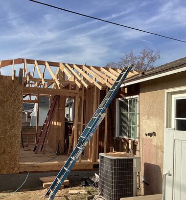 A house under construction featuring a ladder and roof framing in progress.