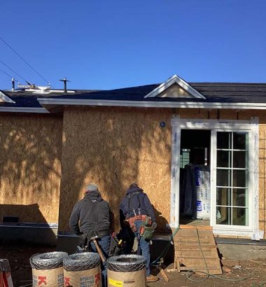 Two men are collaborating on a house under construction, focusing on building and assembly tasks.