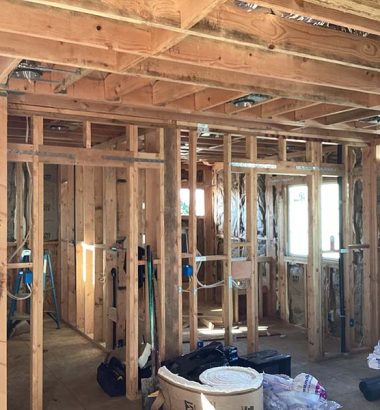 A room featuring exposed wood framing and insulation materials, showcasing the construction process.