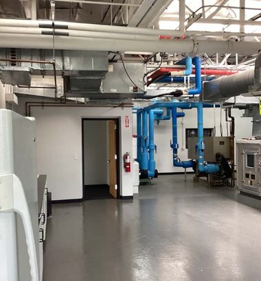 A spacious industrial room filled with various pipes and equipment, indicating a mechanical or engineering environment.