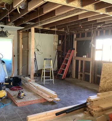 A room filled with various construction equipment and stacks of wood, indicating an active building project.
