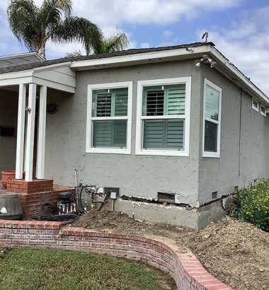 A house featuring a brick wall and a matching brick patio, set in a landscaped outdoor area.