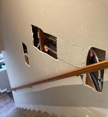 A broken stairway with visible holes in the wall, indicating disrepair and potential safety hazards.