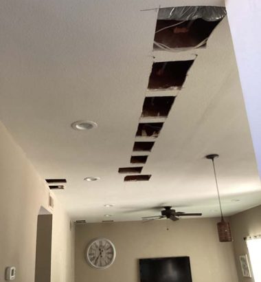 Ceiling with multiple holes and a television mounted on the wall below, indicating possible damage or renovation work.