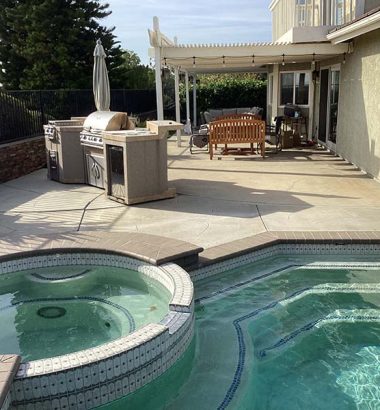 A swimming pool surrounded by patio furniture and a grill, ideal for outdoor relaxation and gatherings.