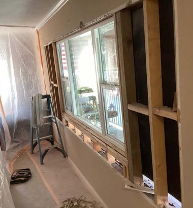 A room featuring a window frame and a ladder against the wall, with natural light illuminating the space.