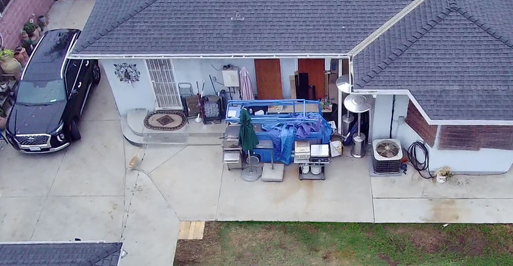 Aerial view of a house with a car parked in front, showcasing the roof and surrounding landscape.