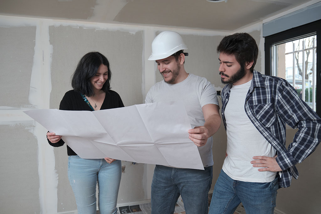 Homeowners planning remodels with contractor and reviewing blueprints.